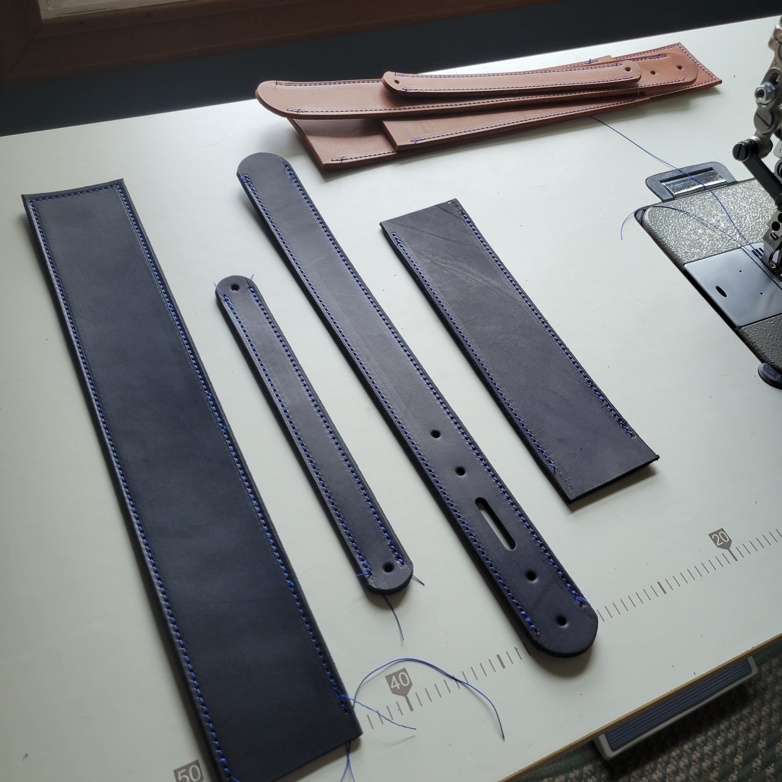 Cut strap pieces laid out on the bench against a ruler