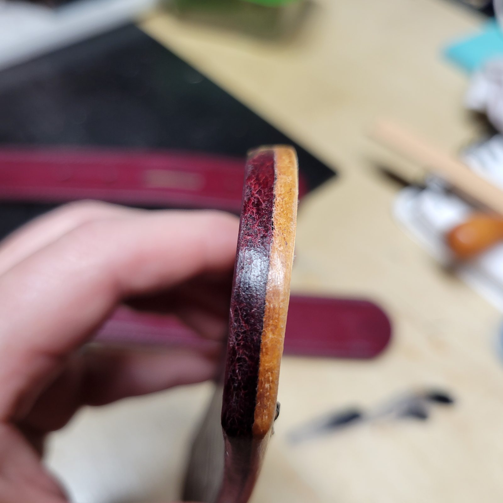 An edge being slicked smooth by hand with a wooden burnisher